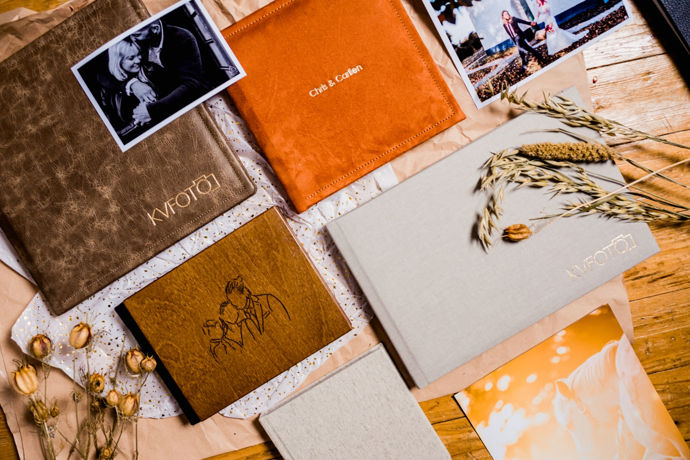 Verschillende handgemaakte trouwalbums, inclusief een leren album en een met een geïllustreerde kaft, samen met polaroids en decoratieve details.