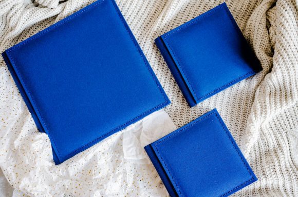 Luxe trouwalbums in verschillende formaten met blauwe kaften, op een zachte achtergrond van een gebreid kleed.